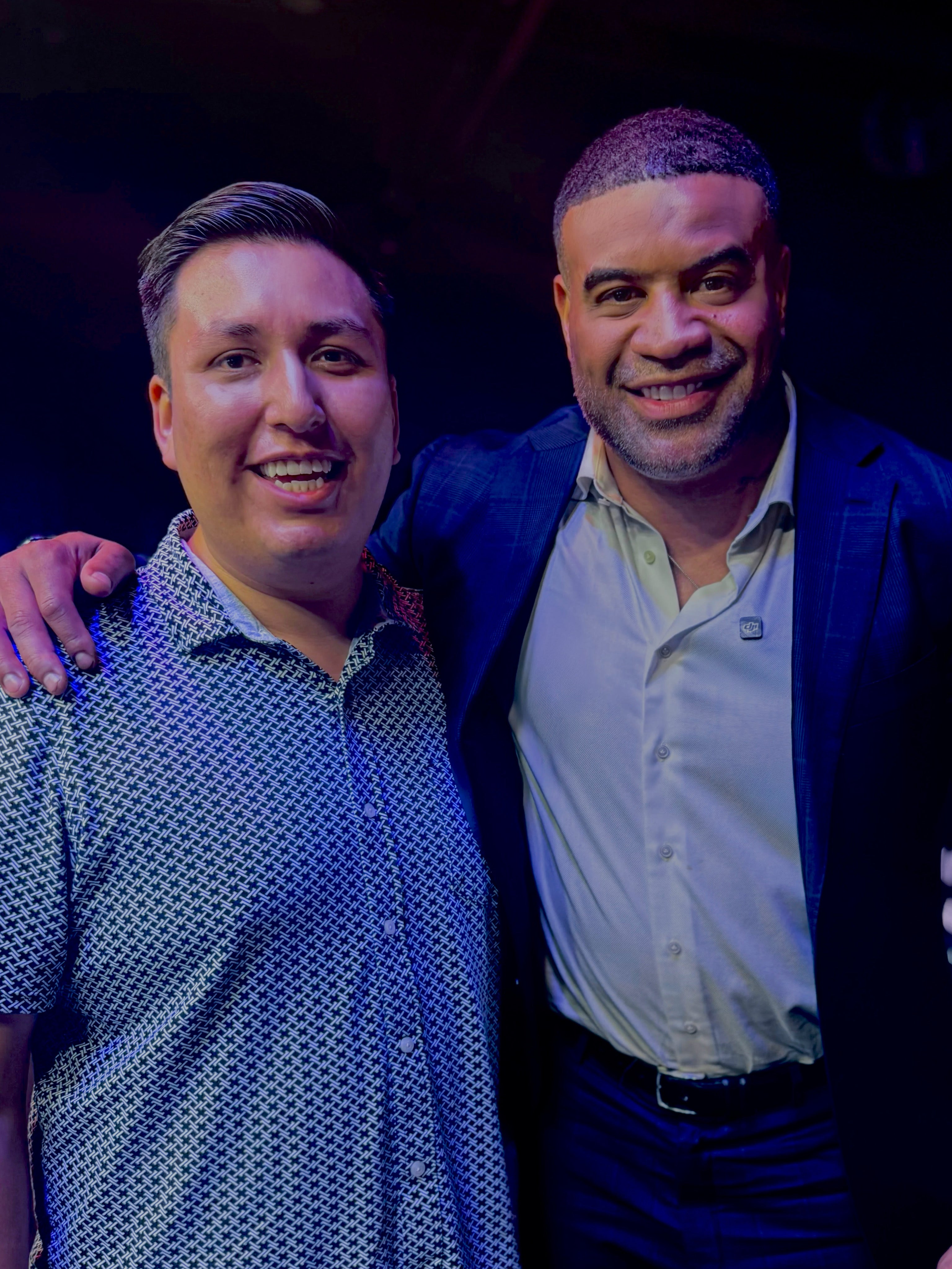 Two men posing together with a dark background